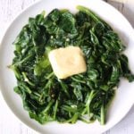 Sauteed spinach is topped with butter.