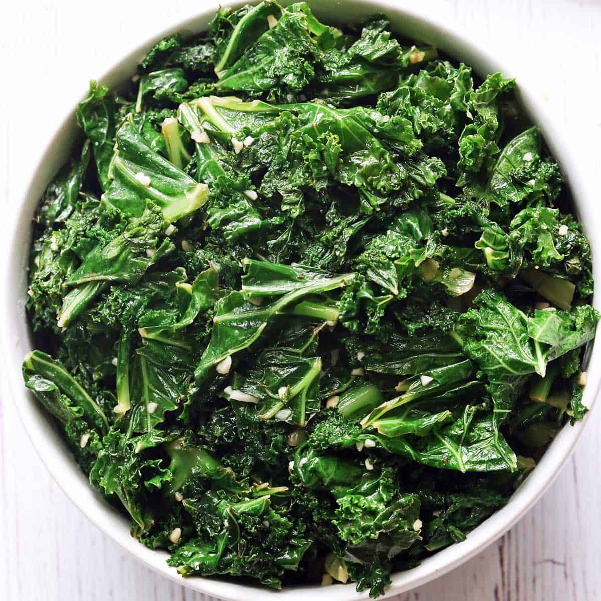 Sauteed kale is served in a white bowl.
