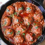 Meatballs in tomato sauce are served in a cast-iron skillet.