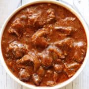 Slow cooker goulash is served in a white bowl.