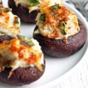 Crab stuffed mushrooms are served on a white plate.