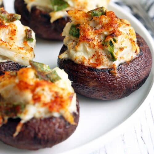 Crab stuffed mushrooms are served on a white plate.