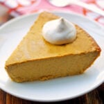 Keto pumpkin cheesecake is topped with a dollop of whipped cream.