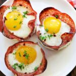 Salami and egg cups are served on a white plate.