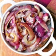 Roasted red onions are served in a white bowl.
