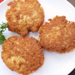 Chicken patties are served on a white plate with parsley for garnish.