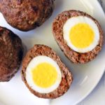 Baked Scotch eggs are served on a white plate.