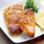 Keto fried fish is served with lemon slices and parsley.