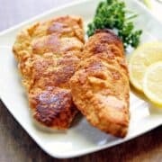 Keto fried fish is served with lemon slices and parsley.
