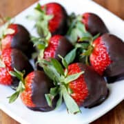 Chocolate-covered strawberries are served on a white plate.