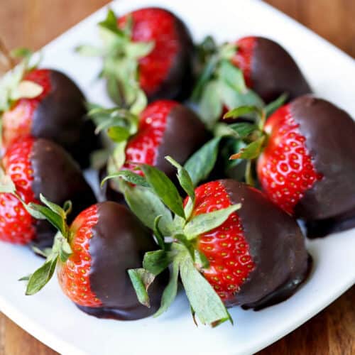 Chocolate-covered strawberries are served on a white plate.