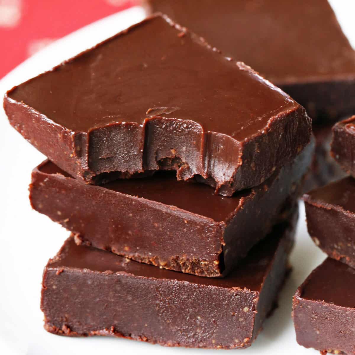 Keto fudge squares are stacked on a white plate.