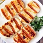 Grilled halloumi cheese is served on a white plate.