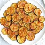 Zucchini chips are served on a white plate.