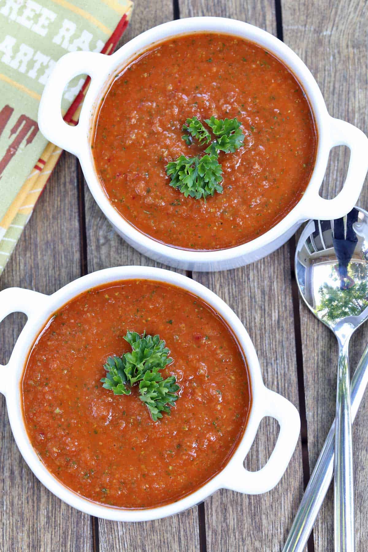 Gazpacho soup served in white bowls with spoons.