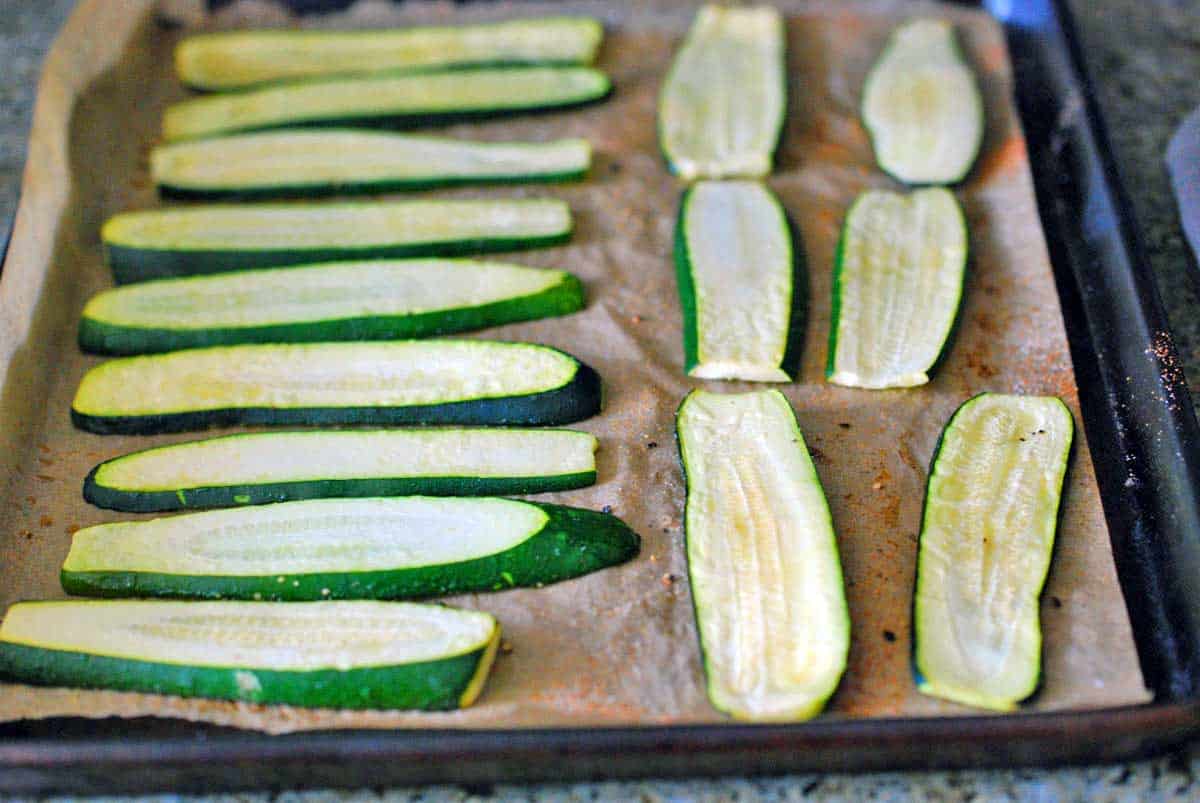 Zucchini slices arranged on a baking sheet.