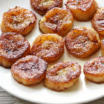 Fried bananas are served on a white plate.