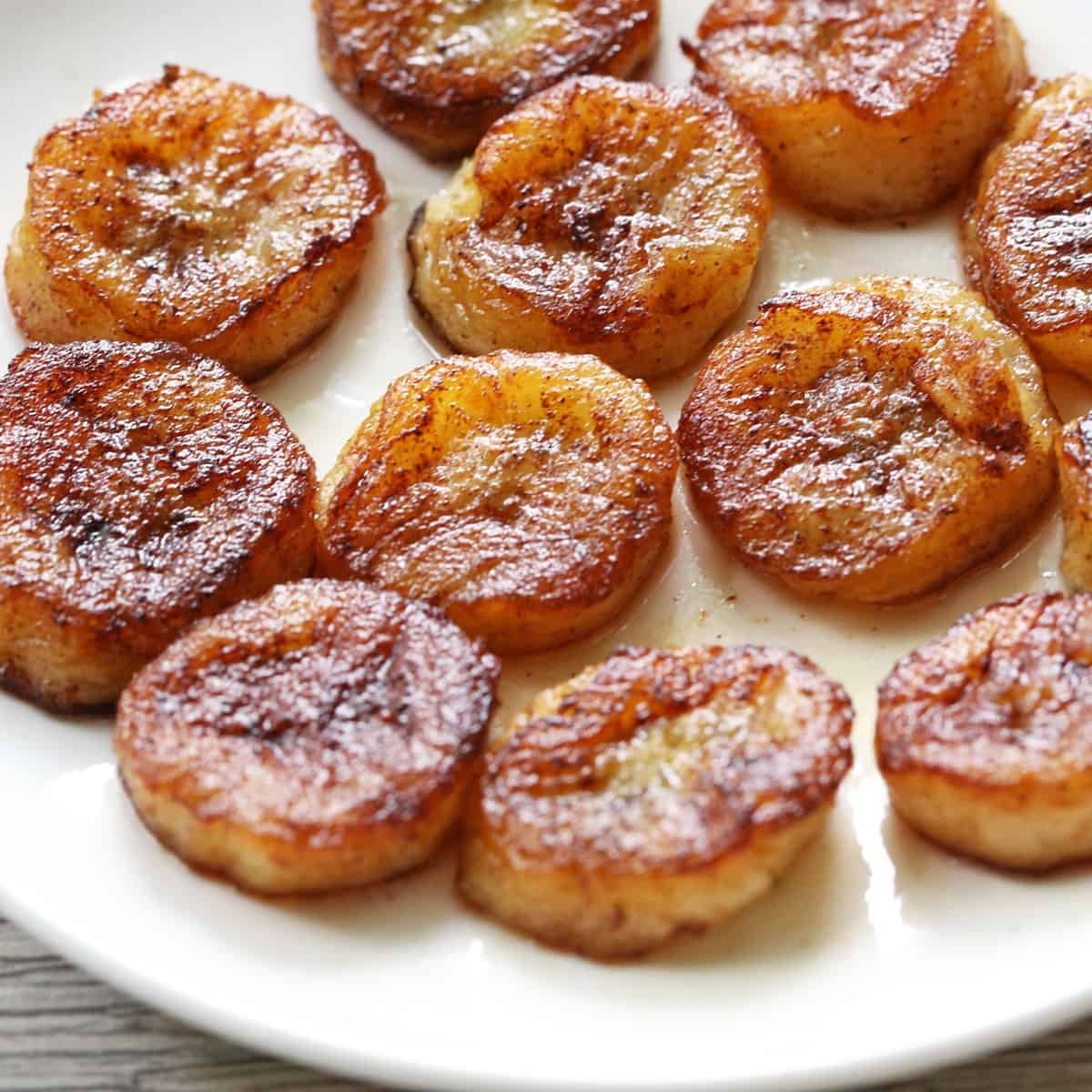 Fried bananas are served on a white plate.