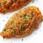 Parmesan-crusted chicken is topped with chopped parsley.