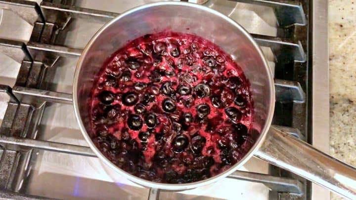 Cooking the blueberries until they are soft.
