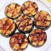 Grilled zucchini is served on a white plate.