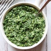 Creamed spinach is served in a white bowl.
