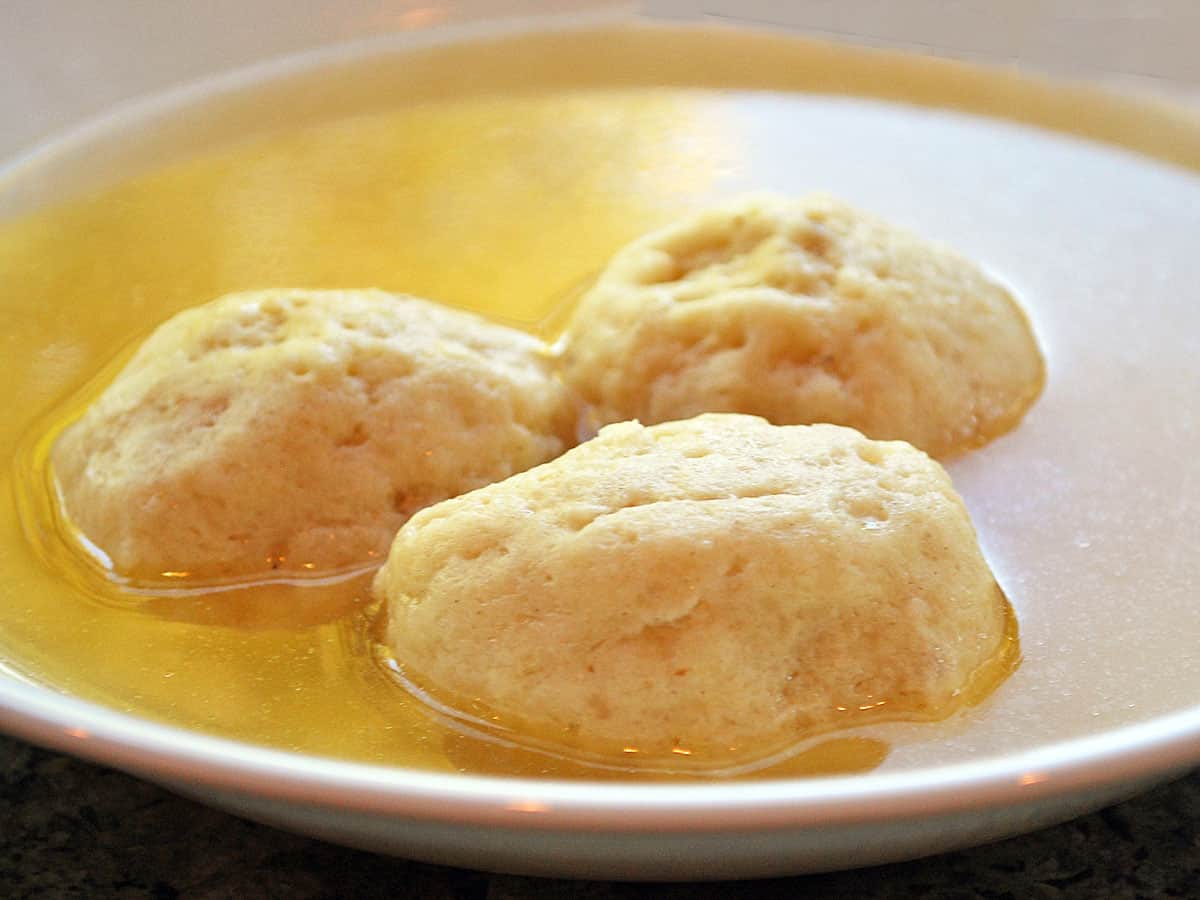Matzo ball soup served in a white soup bowl.