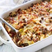 Cabbage casserole is served in a white baking dish with a serving spoon.