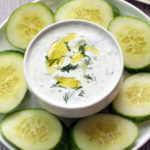 Tzatziki sauce is served with cucumber slices.