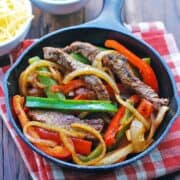 Steak fajitas are served in a cast-iron skillet.