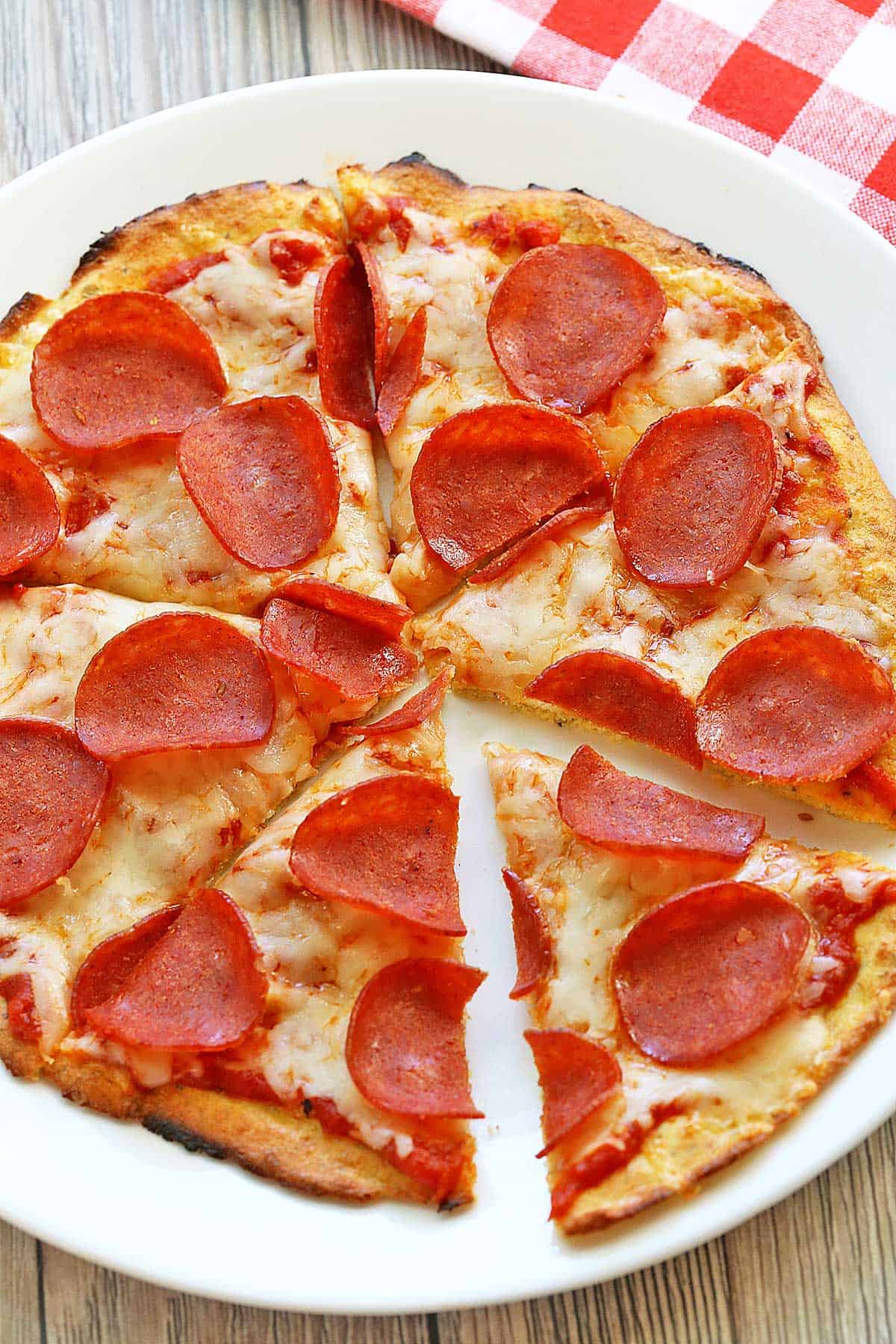 Sliced coconut flour pizza is served on a plate.