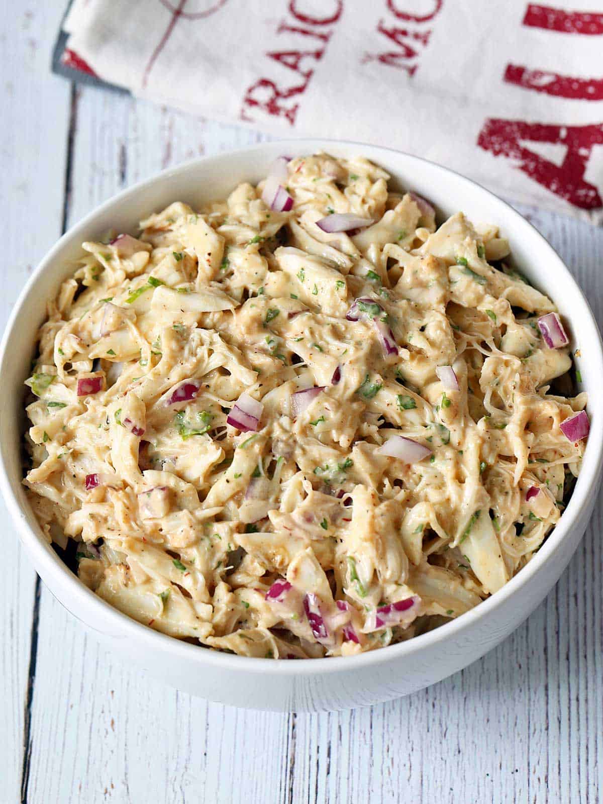 Crab salad is served in a white bowl with a napkin. 
