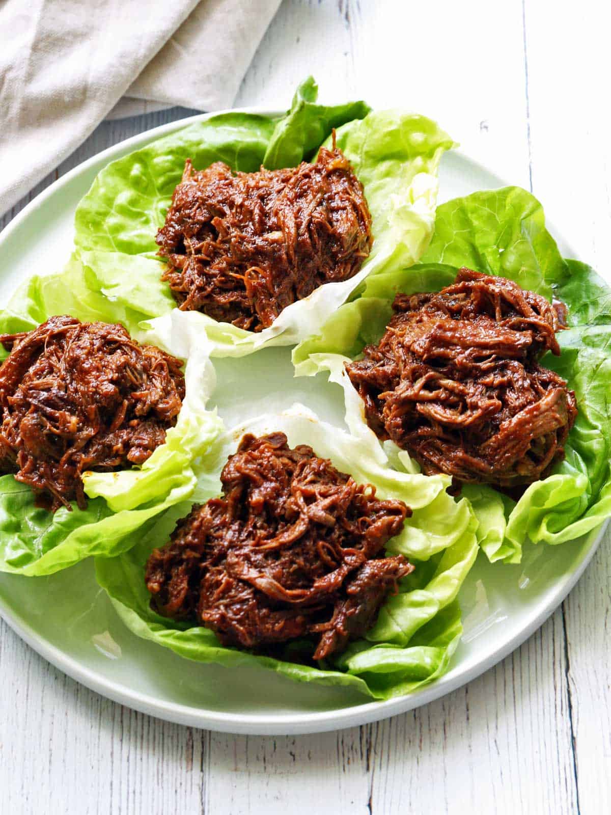 Pulled beef is served in lettuce wraps with a napkin. 