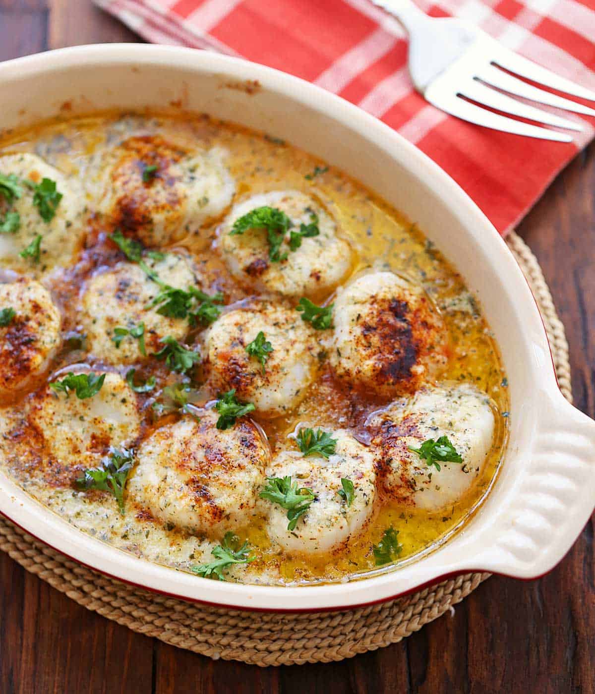 Baked scallops are served in a ceramic baking dish.