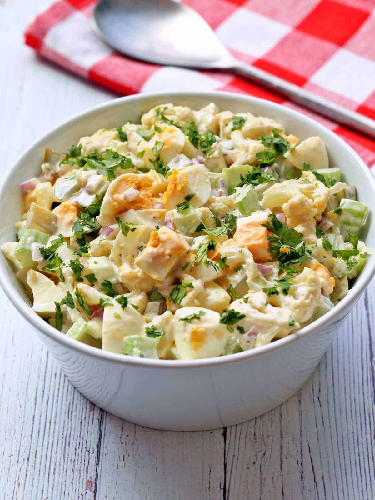 Cauliflower potato salad is served in a white bowl. 