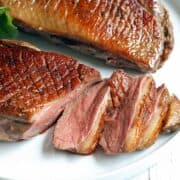 Duck breast, sliced, is served on a white plate.