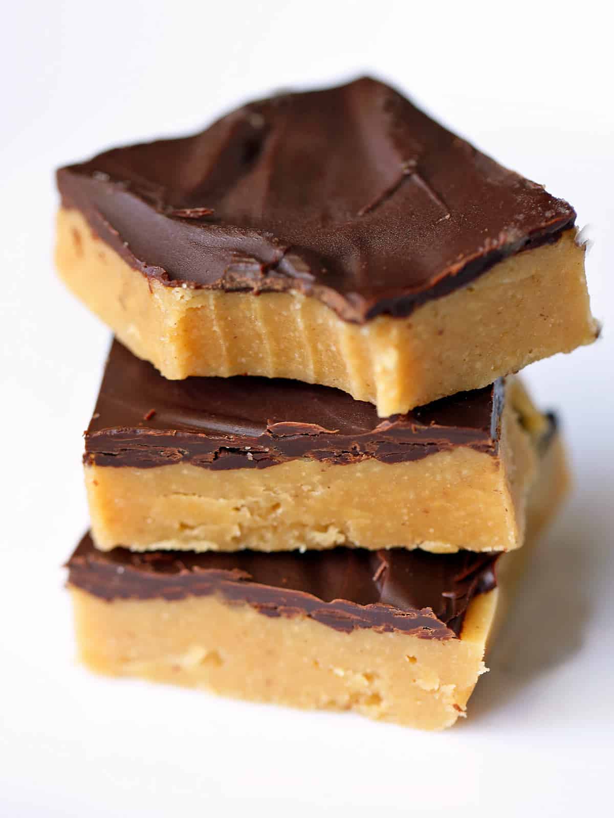 Keto peanut butter bars are stacked on a white plate. 