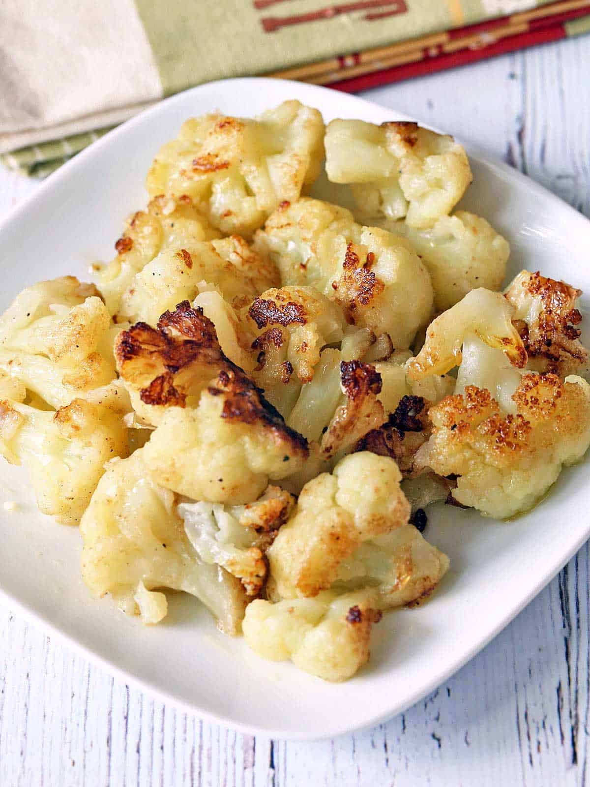 Sauteed cauliflower florets are served on a white plate with a napkin. 