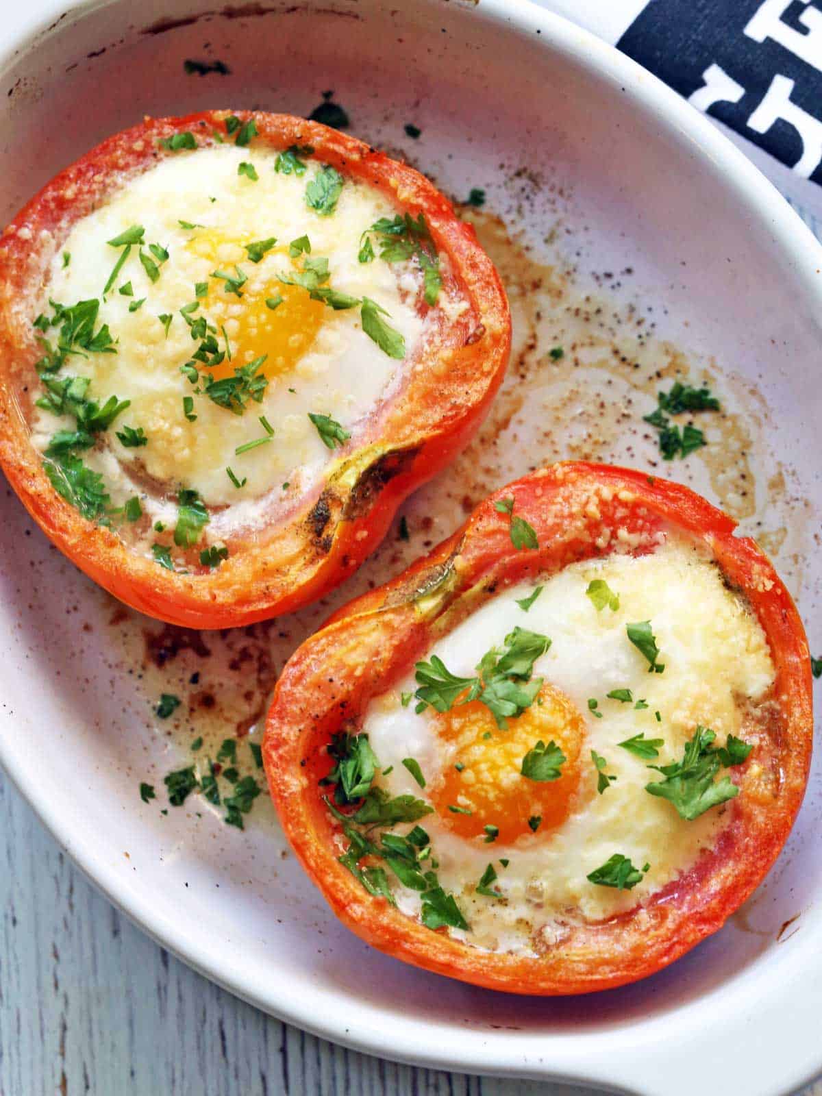 Egg-stuffed breakfast tomatoes are served in a white baking dish.