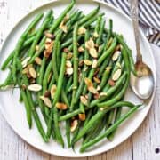 Green beans almondine are served on a white plate.
