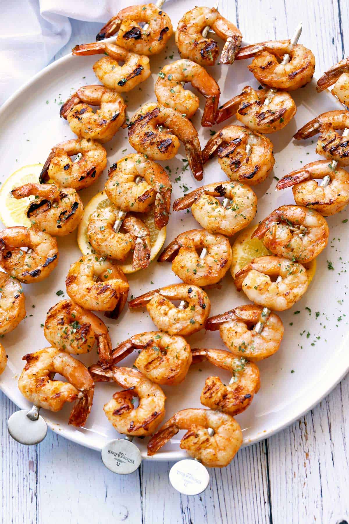 Grilled shrimp on skewers are served on a white platter.