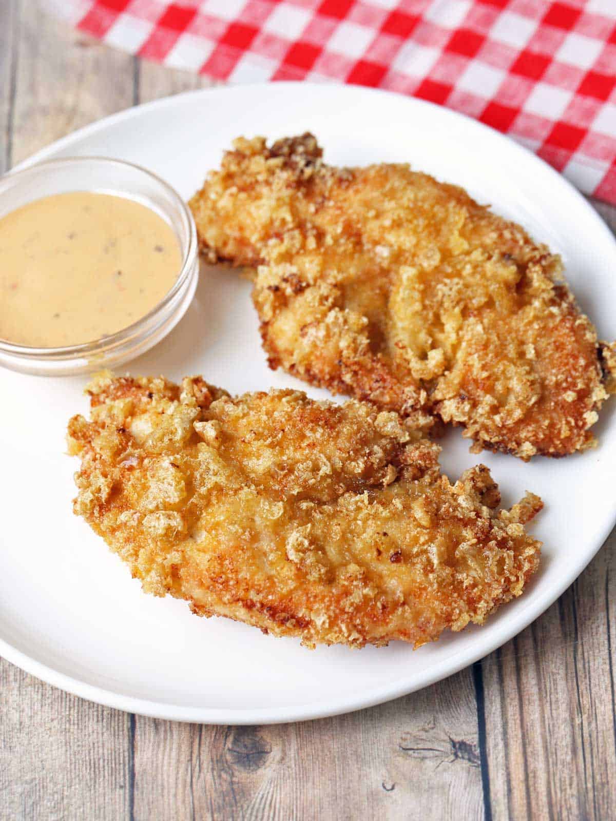 Pork rind chicken tenders are served with a dipping sauce. 