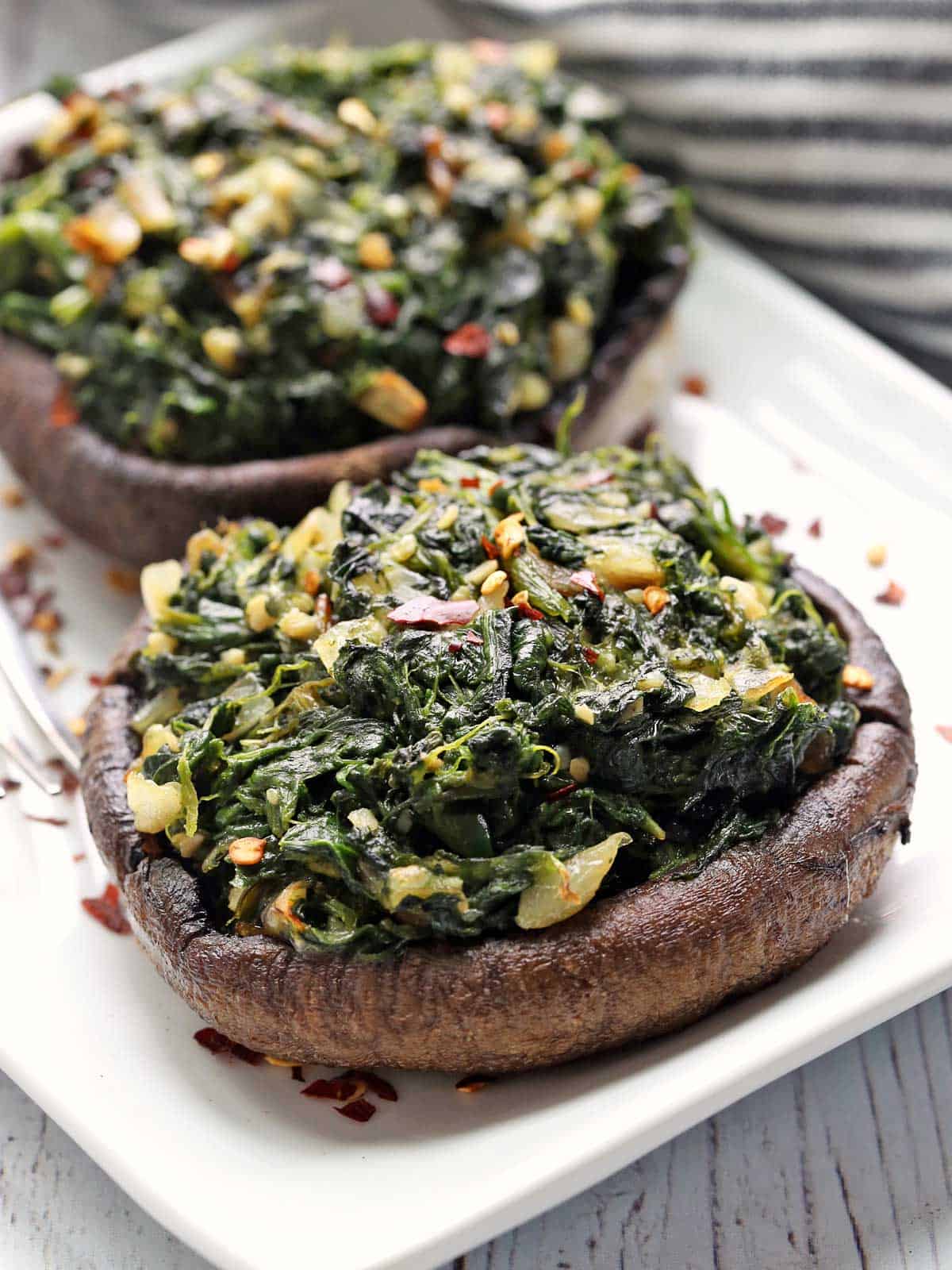 Stuffed portobello mushrooms are served on a white plate.