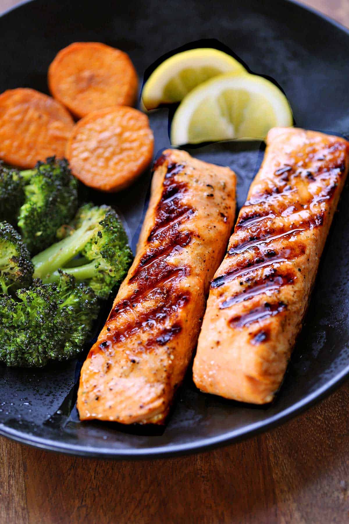 Two pieces of grilled salmon served with sweet potato and broccoli.