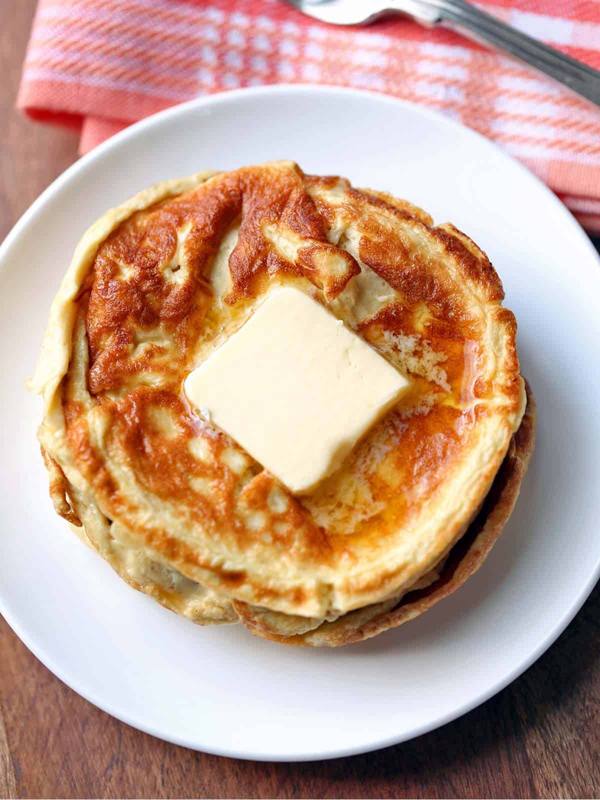 Cream cheese pancakes are topped with butter. 