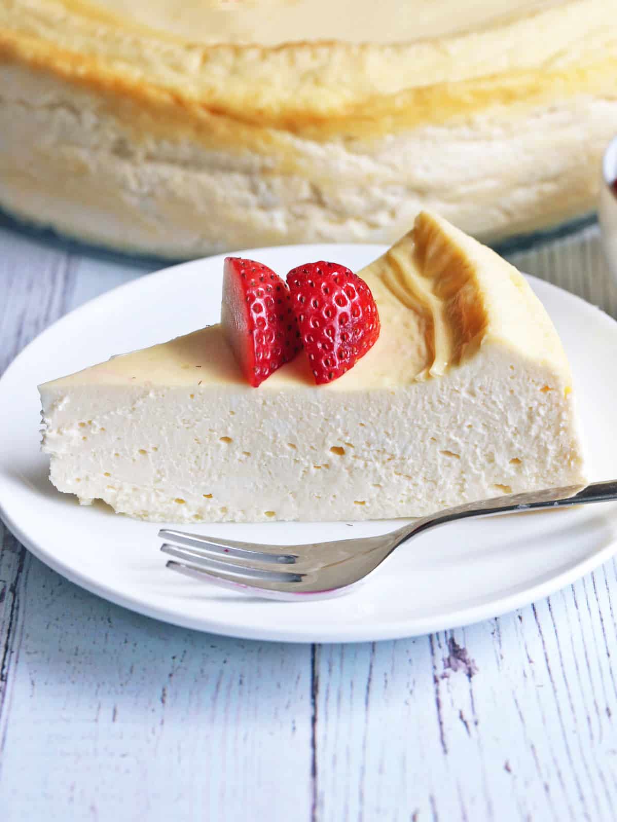 A slice of keto cheesecake is topped with strawberries.
