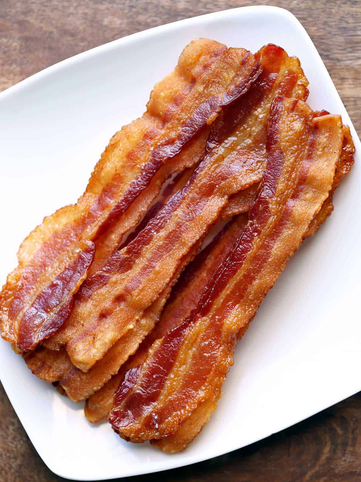 Oven-cooked bacon is served on a white plate.