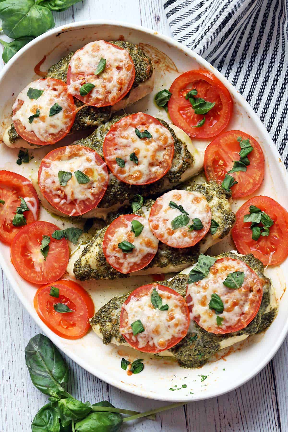 Pesto chicken served on a white platter, garnished with tomatoes.