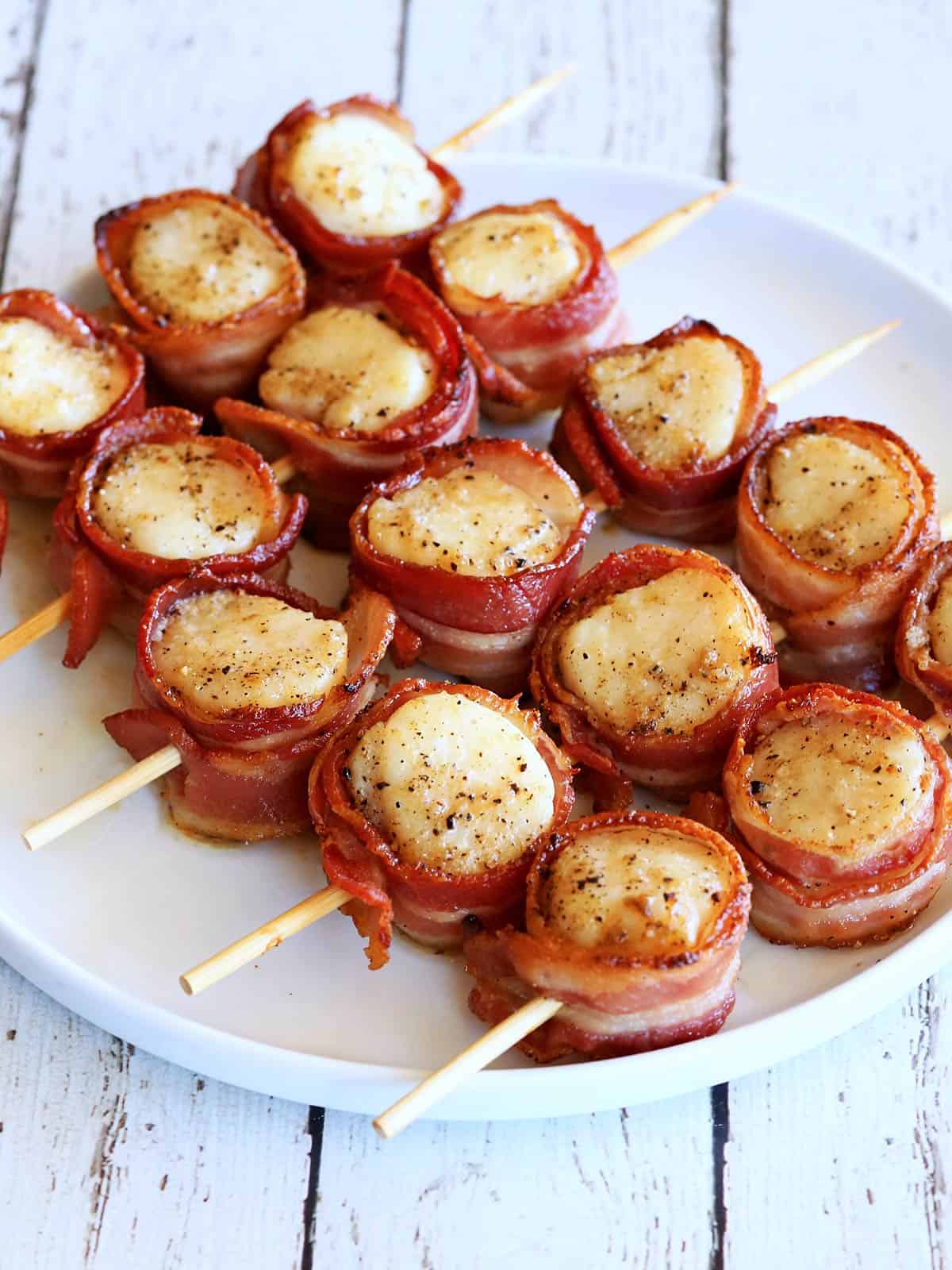 Bacon-wrapped scallops threaded on skewers.