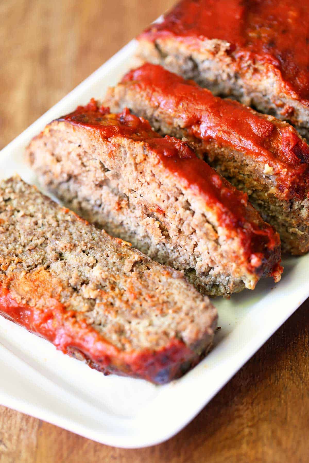 Keto meatloaf, sliced and served on a white serving tray.